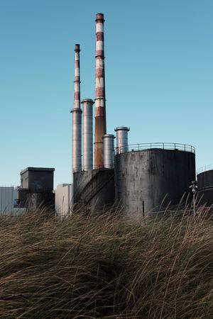 Two tall chimneys with grass in the foreground. The chimneys are the Poolbeg chimneys.